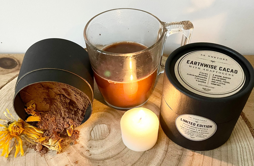 Cup of cacao, candle, and Earthwise Cacao product on a wooden surface with 'Earthwise' branding.
